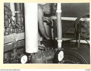 LAE, NEW GUINEA. 1944-11-15. NX171210 CRAFTSMAN A.J. STONHAM, 2/7TH ADVANCED WORKSHOPS OPERATING THE "CONTINENTAL" MOTOR OF THE ONLY AUSTRALIAN OXYGEN GENERATING PLANT IN NEW GUINEA. THIS IS A 6 ..