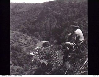 ROUNA FALLS, NEW GUINEA. 1943-11-05. WARRANT OFFICER 1 J. MURPHY OF THE DIRECTORATE OF MILITARY TRAINING, LAND HEADQUARTERS, LOOKING TOWARDS ROUNA FALLS FROM THE CHECK POINT