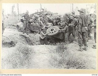 HANSA BAY, NEW GUINEA. 1944-07-20. TROOPS OF THE 4TH INFANTRY BATTALION UNLOADING THEIR GEAR FROM A CAPTURED JAPANESE ARMY TRUCK AFTER IT HAD SLIPPED INTO A DITCH DURING THE UNIT ADVANCE TO THEIR ..