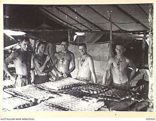 ILIPEM, NEW GUINEA. 1945-08-26. MEMBERS OF A FIELD BAKERY WITH BUNS MADE FOR USE AS BREAD. THEY ARE READY FOR TRANSPORTATION TO FORWARD TROOPS OF 2/5 INFANTRY BATTALION