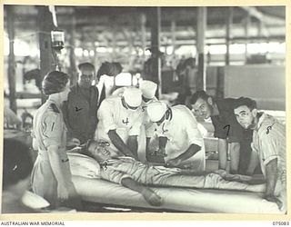 SOUTH ALEXISHAFEN, NEW GUINEA. 1944-08-08. WALKING PATIENTS FIND HUMOUR IN ANOTHER PATIENTS NX120186 LIEUTENANT D.C. MURRAY, 4TH INFANTRY BATTALION (3), GETTING A BLOOD TRANSFUSION AT THE 111TH ..
