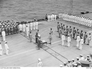 AT SEA OFF RABAUL, NEW BRITAIN. 1945-09-06. THE SURRENDER CEREMONY ON BOARD THE AIRCRAFT CARRIER HMS GLORY. LIEUTENANT GENERAL V.A.H. STURDEE, GENERAL OFFICER COMMANDING FIRST ARMY READS SURRENDER ..