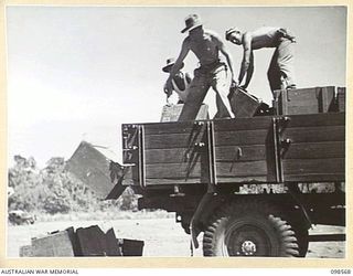 MALAHANG BEACH, LAE, NEW GUINEA. 1945-10-16. TROOPS OF FIRST ARMY DESTROYED SURPLUS AMMUNITION AT MALAHANG BEACH. THEY ARE SHOWN UNLOADING BOXES OF AMMUNITION FROM A TRUCK