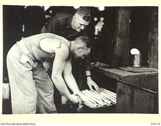 SIAR, NEW GUINEA. 1944-08-09. Q21901 WARRANT OFFICER II, M. OLSEN, 25TH INFANTRY BATTALION (2) INSPECTING SAUSAGE ROLLS AS THEY ARE BEING TAKEN FROM THE OVEN BY QX55929 PRIVATE C. LIESCH