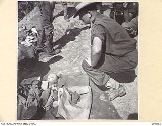 MOUNT SHIBURANGU, WEWAK AREA, NEW GUINEA. 1945-09-21. LANCE CORPORAL N. RYAN, HEADQUARTERS 6 DIVISION, AT A CONTROLLING POINT AT MAKOW ON THE TOP OF MOUNT SHIBURANGU, CHECKING OVER THE PERSONAL ..