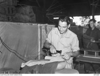 TOROKINA, BOUGAINVILLE. 1945-05-07. PRIVATE F.V. MINEAR (1) PRESSING A UNIFORM AT 4 SECTION OFFICERS' SHOP. SERGEANT H. PRETSEL (2), IS IN THE BACKGROUND