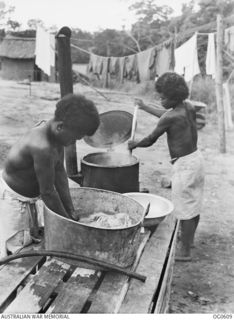 GOODENOUGH ISLAND, PAPUA. 1943-09. AT NO. 2 MEDICAL RECEIVING CENTRE (DETACHMENT), NATIVE PAPUAN LAUNDRY WORKERS IN THE OUTSIDE LAUNDRY BOILING THE CLOTHES AND SCRUBBING THEM IN A TUB