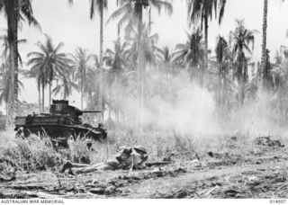 Australian-manned General Stuart M3 Light Tanks bust Japanese pillboxes in the final assault on Buna. Members of D Company, 2/12th Battalion, await the order to move forward after the tank has ..