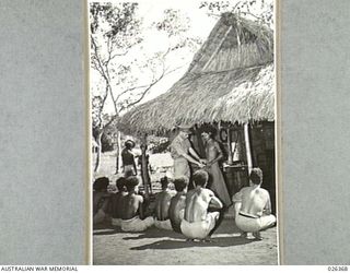 NEW GUINEA. 1942-08. NATIVES AWAITING OUTSIDE A NATIVE BUILT GRASS HUT WHICH IS THE "SURGERY" OF THE NATIVE HOSPITAL RUN BY THE NATIVE MEDICAL SERVICES