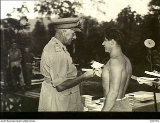 Torokina, Bougainville. 1945-11-04. Major General W. Bridgeford, CB CBE MC, General Officer Commanding 3 Australian Division, presenting a prize to 418295 Leading Aircraftman W. J. MacFarlane, ..