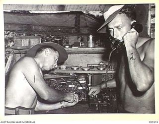 JACQUINOT BAY, NEW BRITAIN, 1945-08-31. SERGEANT R.C. WALSH (1) AND LANCE CORPORAL T.A. BARNES (2), REPAIRING RADIO AND TELEPHONE GEAR IN THE ANTI-AIRCRAFT SIGNAL WORKSHOP AT 141 HEAVY ..