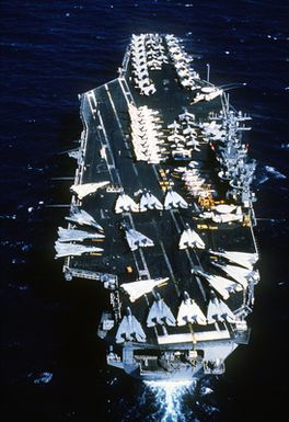 An aerial stern view of the nuclear-powered aircraft carrier USS CARL VINSON (CVN-70) approaching Pearl Harbor, Hawaii. Various types of aircraft are parked along the flight deck of the ship