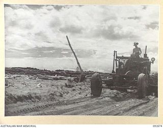 BOUGAINVILLE. 1945-05-30. SAPPER R.B. WALKER, 6 MECHANICAL EQUIPMENT COMPANY ROYAL AUSTRALIAN ENGINEERS, DRIVING A PATROL GRADER ALONG THE BEACH ROAD BETWEEN THE JABA RIVER AND MOTUPENA POINT. THE ..