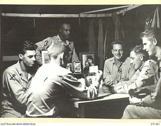 LANGEMAK BAY, NEW GUINEA, 1944-03-20. MEMBERS OF THE 870TH UNITED STATES AVIATION ENGINEER BATTALION PLAYING A CARD GAME. SHOWN HERE : LIEUTENANT G.H. SMITH ( ); LIEUTENANT B.K. LLOYD (2); CHAPLAIN ..