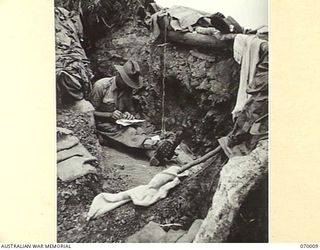 SHAGGY RIDGE, NEW GUINEA. 1944-01-10. VX120804 SERGEANT T.L. CLARKE, OF "A" COMPANY 2/9TH INFANTRY BATTALION WRITES A MESSAGE IN HIS DUGOUT ON THE "PIMPLE"