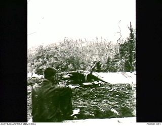 THE SOLOMON ISLANDS, 1945. A LONE AUSTRALIAN SERVICEMAN WATCHING THE RESULT OF A MORTAR SHOOT NEAR THE NUMA NUMA TRAIL ON BOUGAINVILLE ISLAND. (RNZAF OFFICIAL PHOTOGRAPH.)