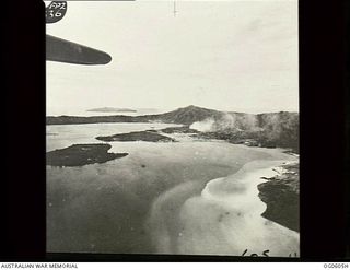 RABAUL, NEW BRITAIN. C. 1944. AERIAL VIEW OF LAKUNAI AERODROME, LOOKING NORTH WEST ACROSS RABAUL TOWN TO WATOM ISLAND IN THE DISTANCE