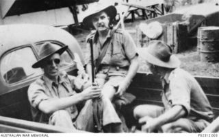 Three members of the Anti Aircraft Battery Rabaul in the back of the battery's Ford utility truck (Registration Number C13605) returning to Malaguna camp after a pig shooting or "puk puk" ..