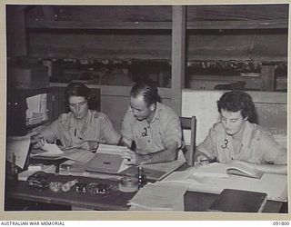 LAE, NEW GUINEA. 1945-05-15. CORPORAL J. HARRIS (1), AND SERGEANT J. GARRETT (3), AT SUPPLY AND TRANSPORT, HEADQUARTERS FIRST ARMY, RECEIVING INSTRUCTION FROM WARRANT OFFICER 2 P.B. COTTERILL (2), ..