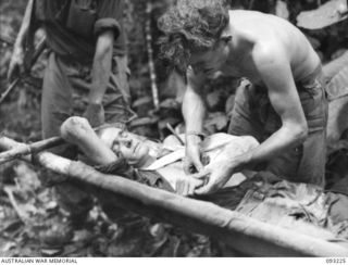 WEWAK AREA, NEW GUINEA, 1945-06-17. PTE R.M. DUFFY, 2/8 INFANTRY BATTALION (2), ATTENDING TO CPL L.H. LENG (1), WHO WAS WOUNDED IN THE ARM DURING A RECONNAISSANCE PATROL TO MIDDLE KNOLL