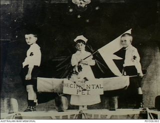 Port Moresby, Papua. c. 1914. Three children of the cast of a patriotic concert entertainment on stage following a performance at the Literary Institute Hall. The boy on the right holding the ..