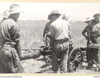 NADZAB AREA, NEW GUINEA. 1944-09-15. PERSONNEL OF THE 2ND MOUNTAIN BATTERY ASSEMBLING THEIR 75MM GUN. HERE THE BOTTOM SLEIGH AND CRADLE HAVE BEEN PLACED ON THE FRONT TRAIL AND THE BREECH RING ..