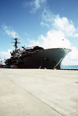 A starboard bow view of the amphibious assault ship USS GUAM (LPH 9) tied up at a pier prior to departing for the Persian Gulf