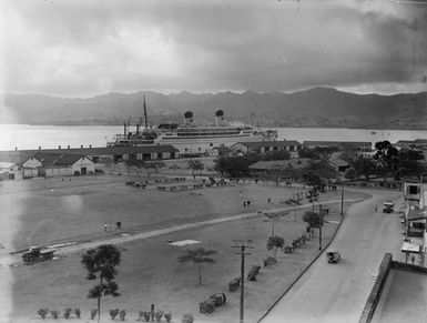 [Long range view of town, ship and mountains]