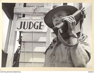 HERBERTON, QLD. 1945-01-20. SERGEANT C N WILSON, 2/7 FIELD REGIMENT, USING A "WALKIE-TALKIE" TO PROVIDE COMMUNICATION BETWEEN THE JUDGES BOX AND BROADCASTING SPEAKERS DURING THE 9 DIVISION GYMKHANA ..