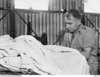 3 MILE, PORT MORESBY, NEW GUINEA. 1943-12-14. NX82290 CORPORAL K. J. WATSON, OF THE 1ST AUSTRALIAN PARACHUTE REFOLDING PLATOON, AUSTRALIAN ARMY ORDNANCE CORPS MAKING REPAIRS TO A DAMAGED PARACHUTE