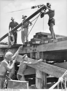 PORT MORESBY, PAPUA, 1944-03-21. MEMBERS OF NO.3 PLATOON, 2/16TH FIELD COMPANY, ROYAL AUSTRALIAN ENGINEERS, PUTTING BRACES FOR WHARF SUPPORT INTO POSITION DURING THE BUILDING OF A NAVAL OILING ..