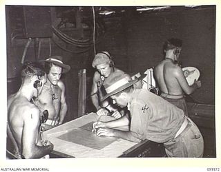 JACQUINOT BAY, NEW BRITAIN, 1945-08-31. CAPTAIN P.S. HILL, PLOTTING OFFICER, 141 HEAVY ANTI-AIRCRAFT BATTERY ROYAL AUSTRALIAN ARTILLERY AND MEMBERS OF THE DETACHMENT AT WORK IN THE PLOTTING ROOM