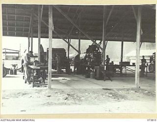 LAE, NEW GUINEA. 1944-06-09. THE INTERIOR OF THE MOTOR TRANSPORT LIGHT REPAIRS SHOP AT THE 2/7TH ADVANCED WORKSHOP. QX47781 CRAFTSMAN C.B. DENNIS (1), IS SHOWN WORKING IN THE FOREGROUND