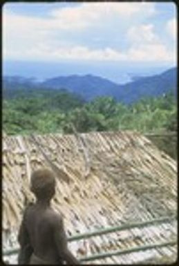 Child overlooking a rooftop onto the sea