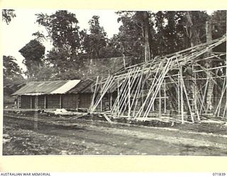 LAE, NEW GUINEA. 1944-03-29. A FIELD STACK OF AMMUNITION AT THE 103RD FIELD AMMUNITION DEPOT. A NEW AND PERMANENT STOREHOUSE IS BEING ERECTED IN THE FOREGROUND