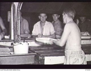 AT SEA. 1944-05-12. MESS ORDERLIES, COLLECTING RATIONS FROM THE GALLEY STAFF OF THE TROOPSHIP ORMISTON DURING THE JOURNEY FROM PORT MORESBY TO LAE