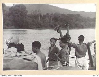 TINIAN, BOUGAINVILLE. 1945-07-18. PASSENGERS ABOARD THE ALLIED INTELLIGENCE BUREAU MOTOR LAUNCH ML1327, WAVING FAREWELL TO NATIVES OF THE ALLIED INTELLIGENCE BUREAU, ON SHORE, AS THE VESSEL LEAVES ..