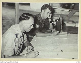 TOROKINA, BOUGAINVILLE. 1945-04-28. FLIGHT LIEUTENANT F. BELL (1) AND SERGEANT R. PERRY (2), MEMBERS OF 5 MOBILE METEOROLOGICAL FLIGHT RAAF, ATTACHED HEADQUARTERS 2 CORPS, WORKING WITH PLOTTING ..