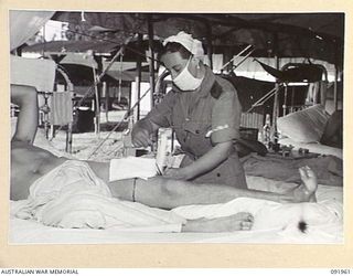 BOUGAINVILLE, 1945-04-18. SISTER E.E.S. LYCETT, AUSTRALIAN ARMY NURSING SERVICE (1), DRESSING THE SHRAPNEL WOUNDS OF A PATIENT AT 2/1 GENERAL HOSPITAL