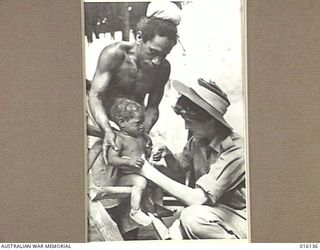 NEW GUINEA. 17 NOVEMBER 1943. NELL BACKHOUSE OF KILLARNEY, QLD, MAKES FRIENDS WITH THE YOUNGEST INHABITANT OF A LOCAL VILLAGE