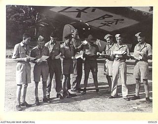 PIVA AIRSTRIP, TOROKINA, BOUGAINVILLE. 1945-08-15. MEMBERS OF THE ROYAL NEW ZEALAND AIR FORCE AND ROYAL AUSTRALIAN AIR FORCE IN HEADQUARTERS 2 CORPS AREA, LOOKING AT SURRENDER LEAFLETS BEFORE ..