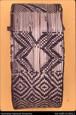 Detail of a partially completed arm band that is woven on a miniature loom around a bark base