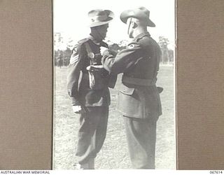 STRATHPINE, QLD. 1944-07-20. QX11325 LANCE-SERGEANT J.M. BALL (1) OF THE 2/25TH INFANTRY BATTALION, RECEIVING THE BRITISH EMPIRE MEDAL RIBBON FROM QX6305 MAJOR T.J.C. O'BRYEN, ADMINISTRATION ..