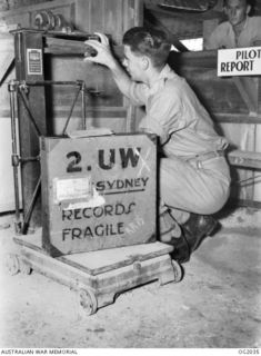 MADANG, NEW GUINEA. C. 1944-10. A PACKAGE OF SOUND RECORDINGS IS WEIGHED BY 143125 LEADING AIRCRAFTMAN N. W. LAURIE, NORTHWOOD, VIC, AT AIR TRANSPORT CONTROL BEFORE RETURN TO THE MAINLAND