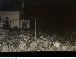 Port Moresby, New Guinea. 1944-05-09. Australian and allied personnel sitting at night on the lawns of St John's Church of England listening to a concert of recorded music