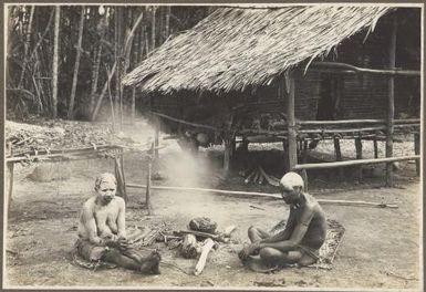 [Man and woman in mourning, sitting near a fire], scene at Ambasi, North Coast, [Papua New Guinea]