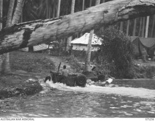 MILILAT, NEW GUINEA. 1944-08-13. VX137730 WARRANT OFFICER II, N.W. GRANGER EMERGING FROM THE WATER AFTER DRIVING A WATERPROOFED JEEP ACROSS A WIDE CREEK NEAR THE CAMP OF THE ELECTRICAL AND ..