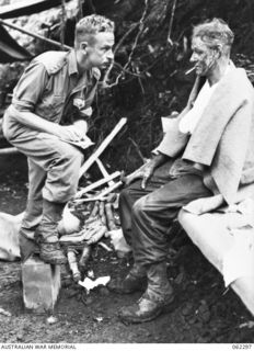 SHAGGY RIDGE, NEW GUINEA. 1943-12-27. VX91417 CAPTAIN J. C. ZWAR (1) MEDICAL OFFICER OF THE 2/16TH AUSTRALIAN INFANTRY BATTALION, 21ST AUSTRALIAN INFANTRY BRIGADE, QUESTIONING NX59198 PRIVATE M. ..