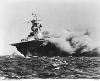 SOUTH PACIFIC OCEAN. 1942-09-15. THE AIRCRAFT CARRIER USS WASP, LISTING AND WITH SMOKE POURING FROM OIL AND GASOLINE FIRES CAUSED BY THREE TORPEDO HITS IN THE STARBOARD SIDE FROM THE JAPANESE ..