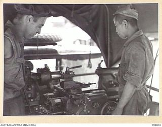 RATAVAL, NEW BRITAIN. 1945-11-17. CRAFTSMAN N. BLIZZARD, 2/4 ARMOURED REGIMENT, AND A JAPANESE SOLDIER OPERATING A LATHE IN A JAPANESE WORKSHOP TRUCK